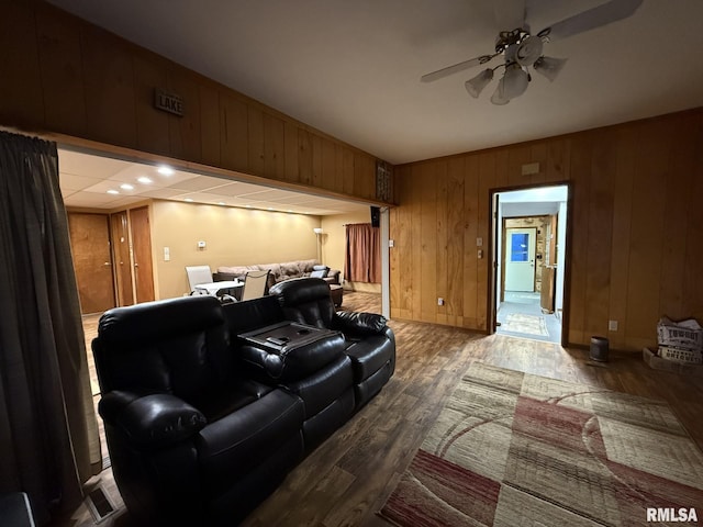 home theater featuring ceiling fan, wood walls, and wood finished floors