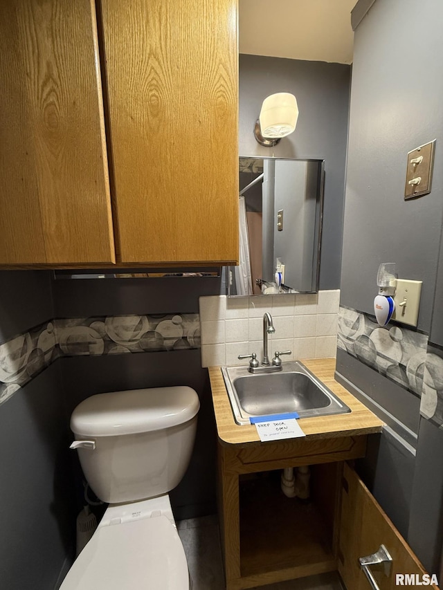 bathroom featuring toilet, backsplash, and sink