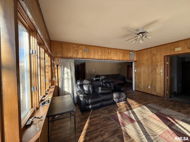 living room featuring ceiling fan, dark hardwood / wood-style floors, and wooden walls