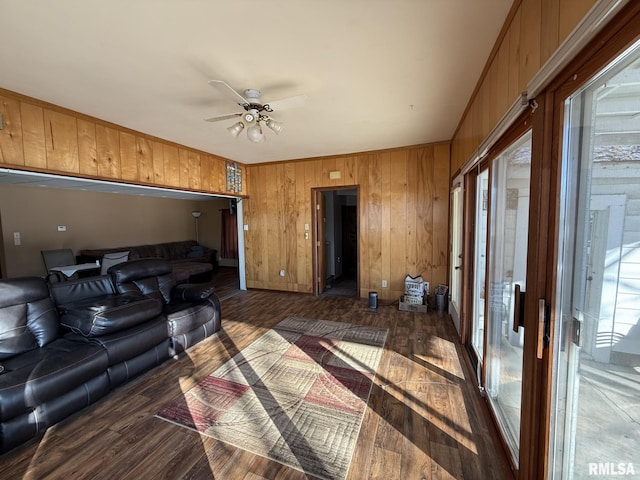 living room featuring ceiling fan, dark hardwood / wood-style floors, plenty of natural light, and wooden walls