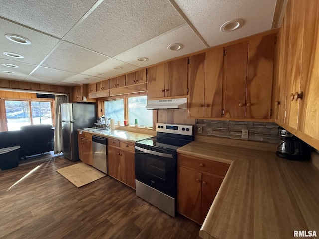 kitchen with dark wood finished floors, stainless steel appliances, light countertops, a sink, and under cabinet range hood