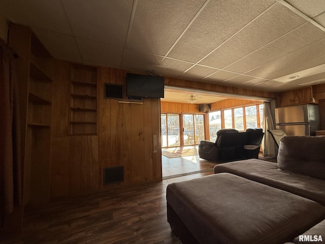 living room featuring ceiling fan, dark hardwood / wood-style floors, and wooden walls