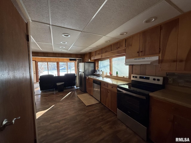 kitchen with stainless steel appliances, dark wood-type flooring, a sink, a drop ceiling, and under cabinet range hood