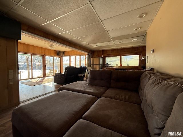 living room featuring wood walls, a drop ceiling, and wood finished floors