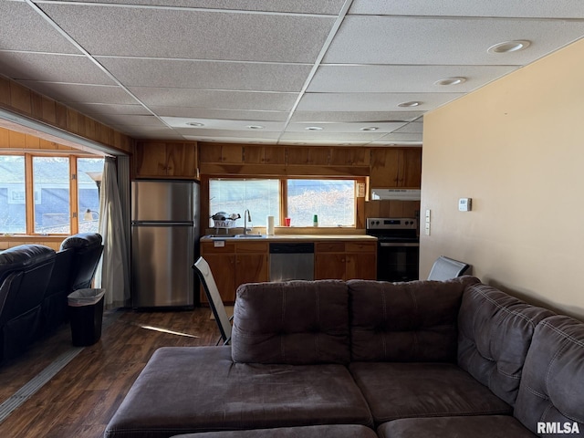 living area with wood walls, dark wood-style flooring, and a drop ceiling