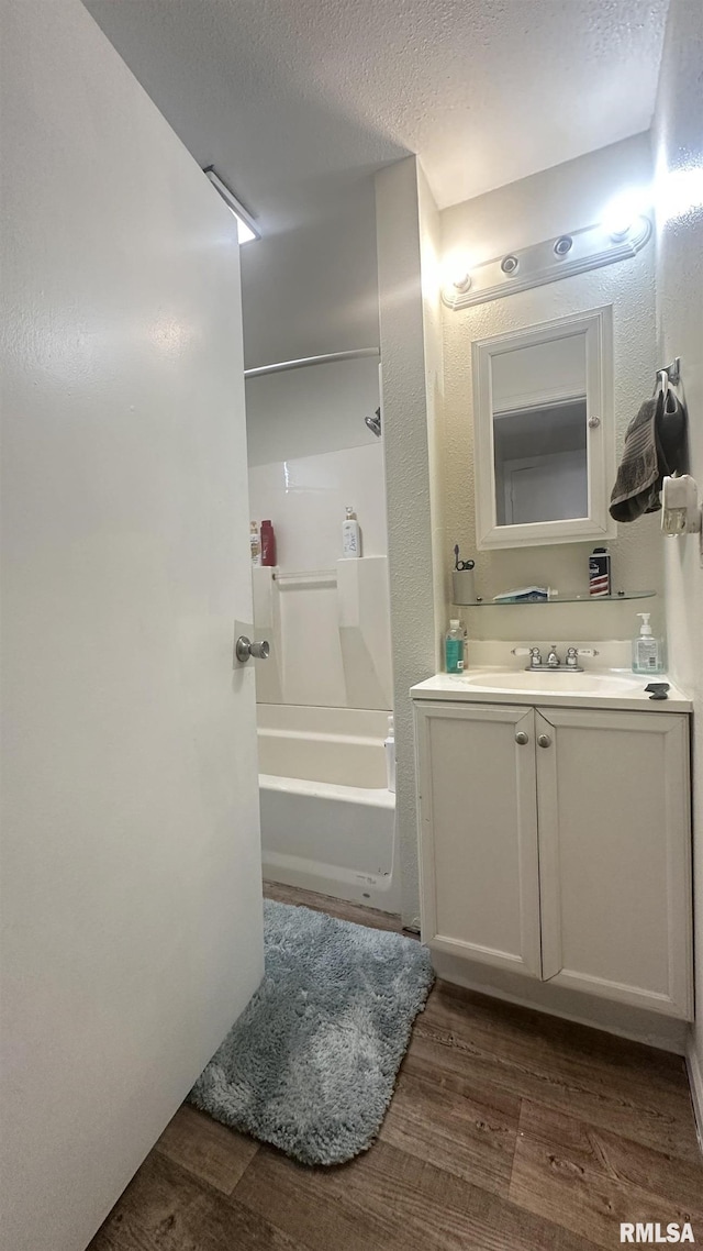 bathroom featuring vanity, hardwood / wood-style floors, a textured ceiling, and shower / bathing tub combination