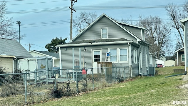 rear view of property featuring a yard and central AC unit