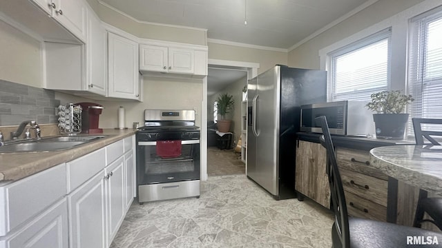 kitchen featuring sink, crown molding, appliances with stainless steel finishes, white cabinets, and backsplash