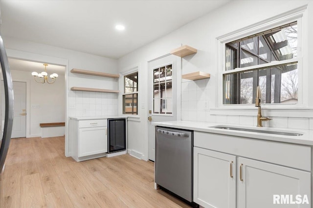 kitchen featuring dishwasher, sink, beverage cooler, decorative light fixtures, and white cabinets