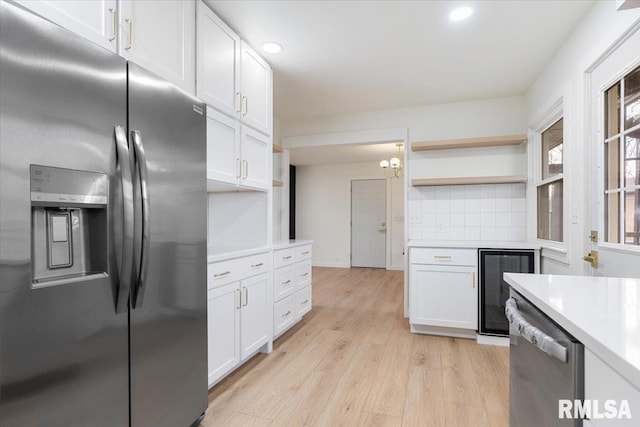 kitchen featuring pendant lighting, stainless steel appliances, white cabinetry, and light hardwood / wood-style floors