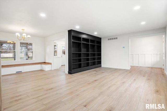 empty room with light hardwood / wood-style flooring and a notable chandelier