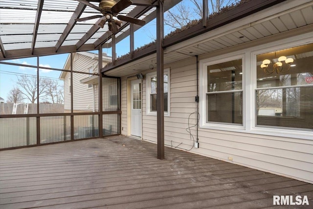 unfurnished sunroom featuring ceiling fan with notable chandelier