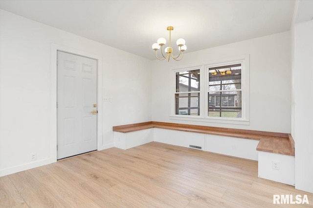 unfurnished room with light hardwood / wood-style floors and an inviting chandelier