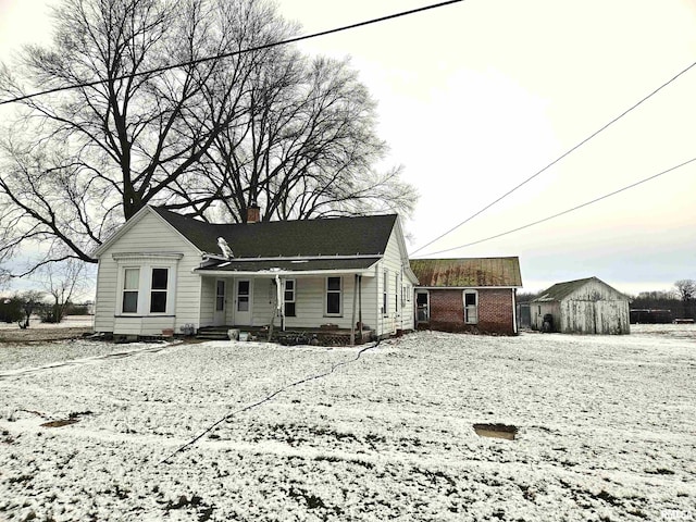 snow covered back of property with a porch