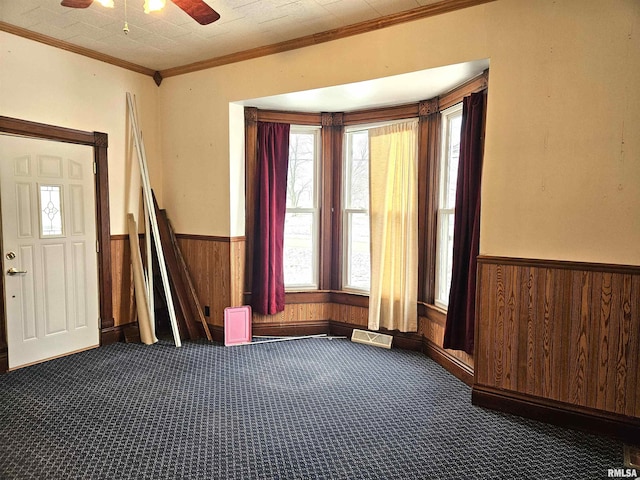 interior space with ceiling fan, crown molding, and carpet floors