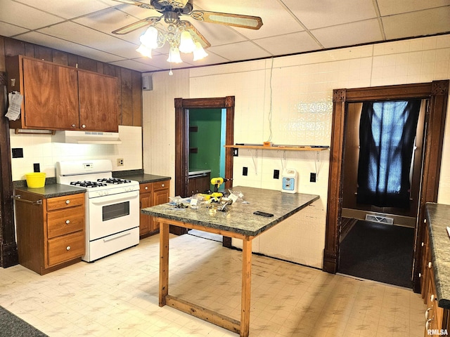 kitchen featuring a drop ceiling, ceiling fan, and gas range gas stove