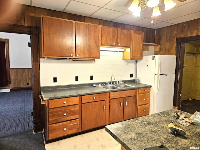 kitchen featuring a paneled ceiling, white fridge, sink, and wooden walls