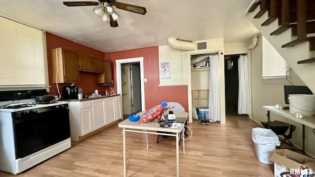 kitchen with white cabinets, ceiling fan, light hardwood / wood-style floors, and white range with gas cooktop