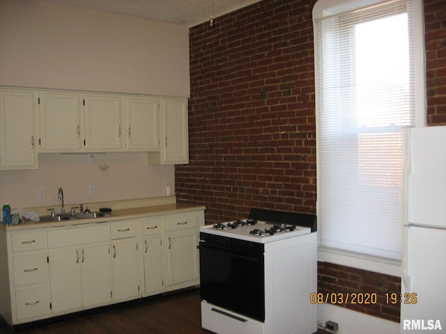 kitchen featuring brick wall, white appliances, sink, white cabinets, and plenty of natural light