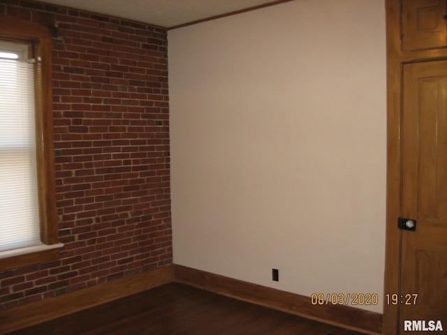 spare room featuring crown molding, brick wall, and dark hardwood / wood-style floors