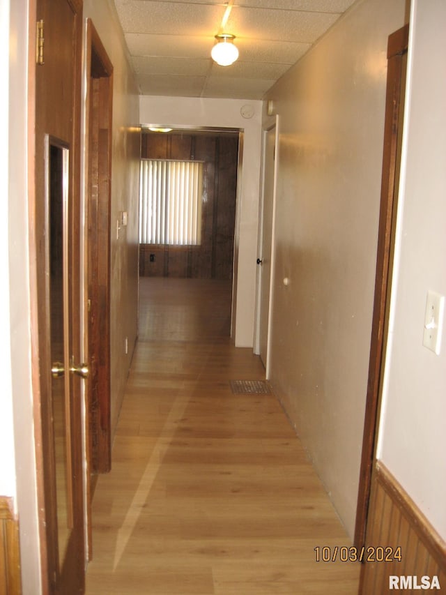 hallway with light hardwood / wood-style floors and wood walls