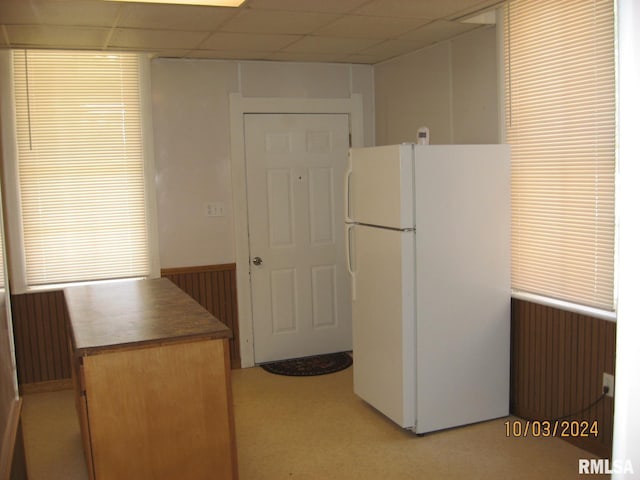 kitchen featuring a paneled ceiling, wood walls, light carpet, white refrigerator, and radiator heating unit