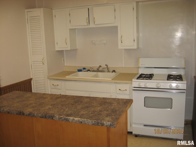 kitchen featuring white cabinets, white gas range, and sink