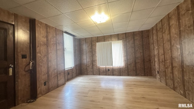 unfurnished room with wooden walls, light hardwood / wood-style floors, and a healthy amount of sunlight