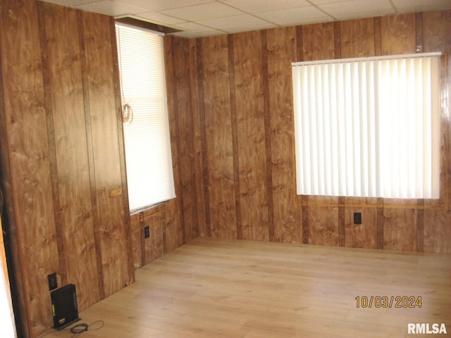 empty room featuring wood walls and light hardwood / wood-style floors