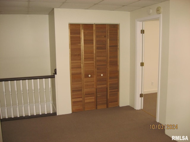 unfurnished bedroom with carpet flooring, a paneled ceiling, and a closet