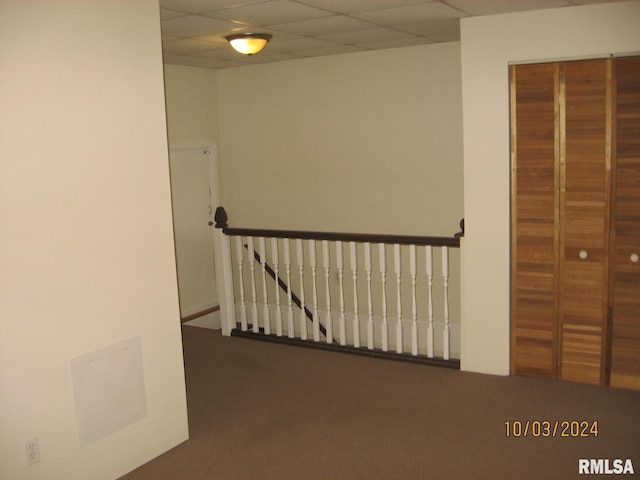 hallway with carpet floors and a paneled ceiling