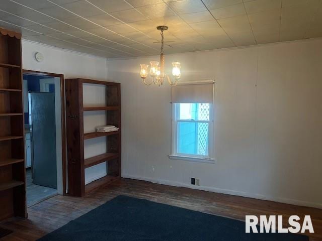 unfurnished dining area with wood-type flooring and an inviting chandelier