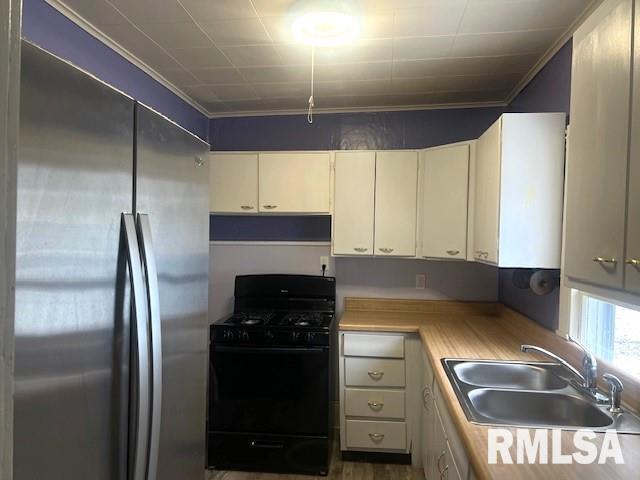 kitchen featuring stainless steel built in fridge, black range with gas cooktop, cream cabinetry, and sink