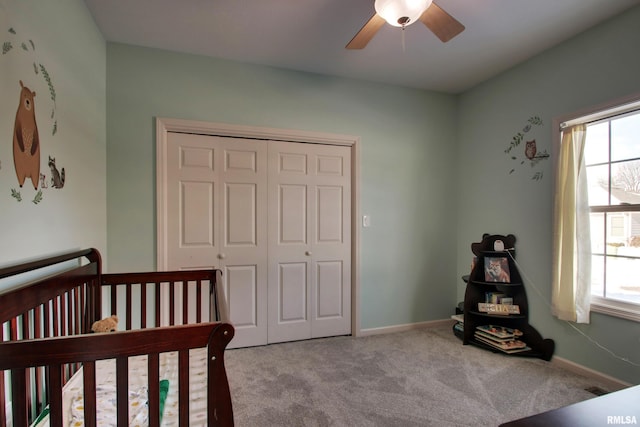 carpeted bedroom featuring ceiling fan, a crib, and a closet