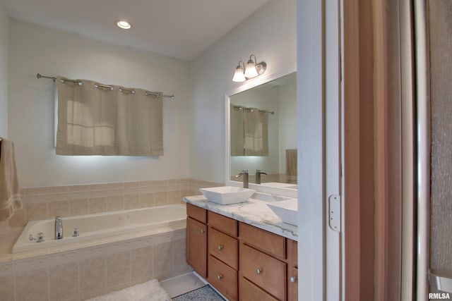 bathroom featuring tile patterned flooring, vanity, and tiled bath