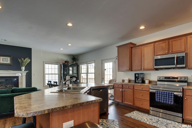 kitchen featuring appliances with stainless steel finishes, dark hardwood / wood-style floors, a kitchen island with sink, and sink