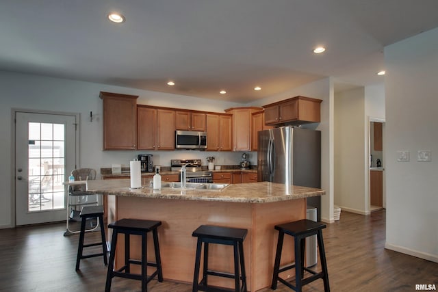 kitchen featuring a kitchen breakfast bar, stainless steel appliances, dark wood-type flooring, sink, and a center island with sink