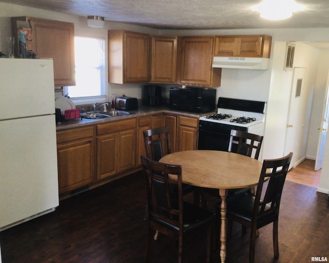 kitchen featuring white appliances, dark wood-type flooring, and sink