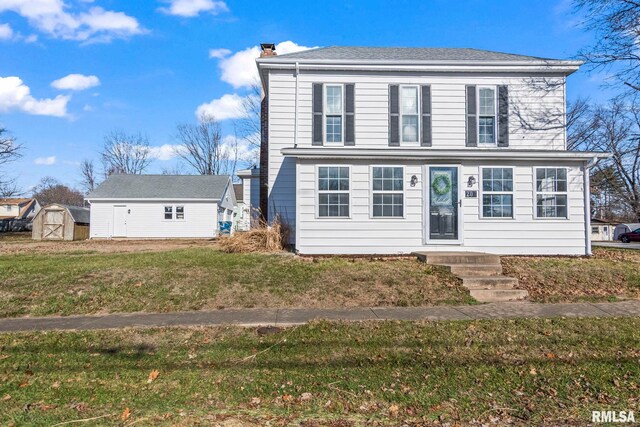 view of front of house with a front lawn and a storage shed