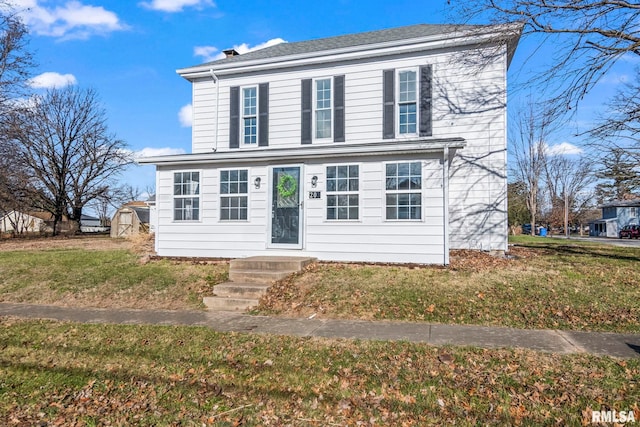 view of front of house with a storage shed and a front yard