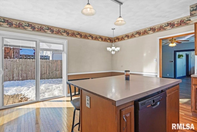 kitchen with decorative light fixtures, a kitchen island, black dishwasher, and ceiling fan with notable chandelier