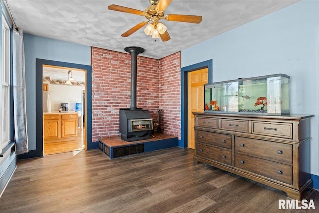 interior space featuring a wood stove, ceiling fan, and dark hardwood / wood-style floors