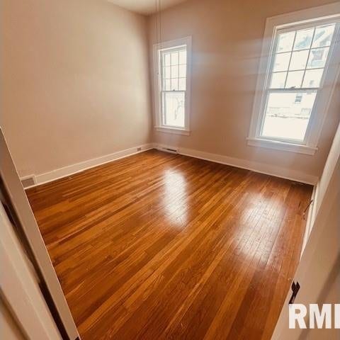 unfurnished room with a healthy amount of sunlight and hardwood / wood-style flooring