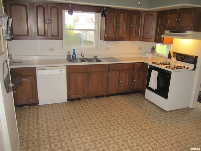 kitchen with white appliances, dark brown cabinetry, and sink