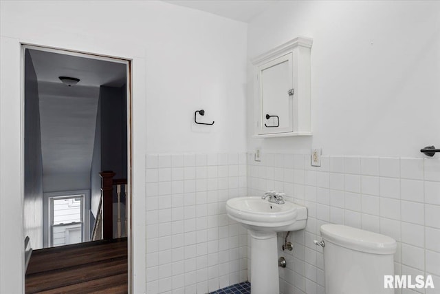 bathroom featuring tile walls and toilet