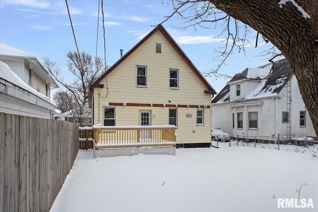 snow covered back of property with a wooden deck