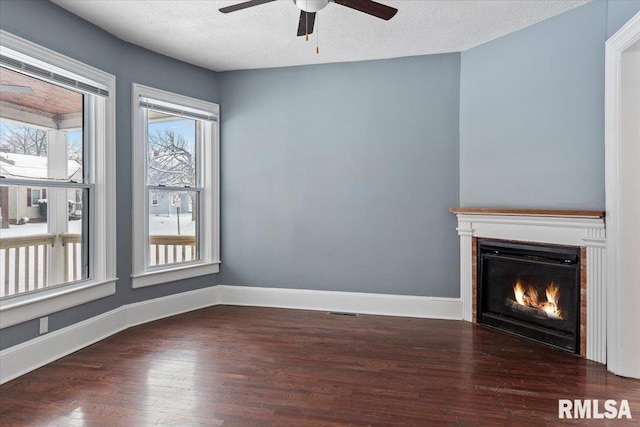 unfurnished living room with ceiling fan, a textured ceiling, and dark hardwood / wood-style flooring