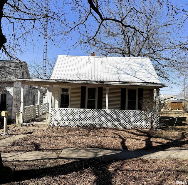 view of front of home featuring a chimney, a porch, and metal roof