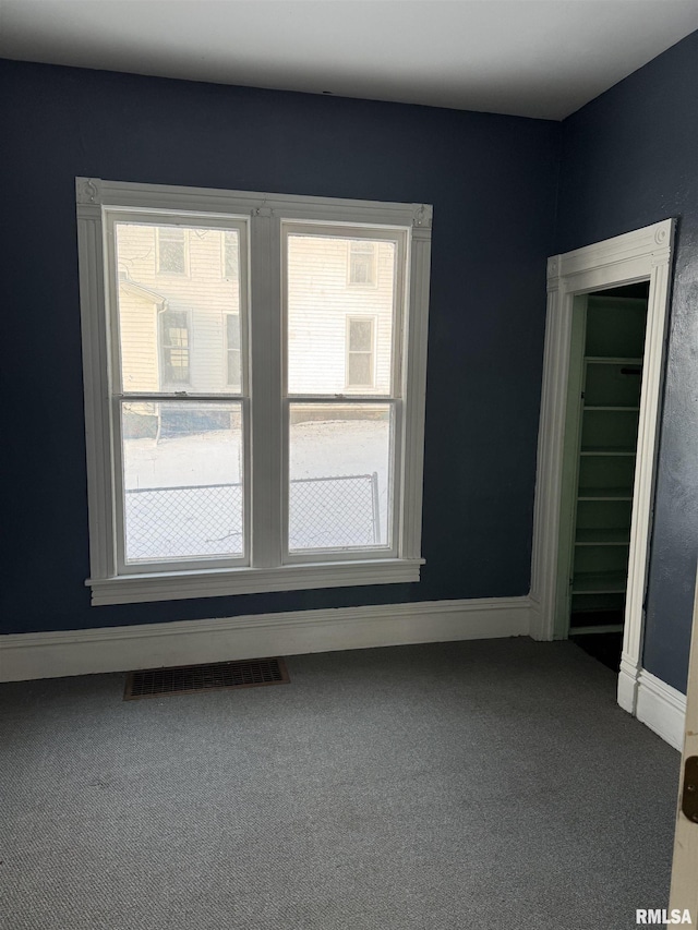 empty room with carpet flooring, baseboards, and visible vents