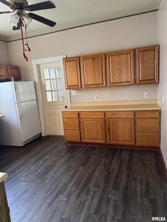 kitchen with crown molding, light countertops, brown cabinets, freestanding refrigerator, and dark wood-style floors